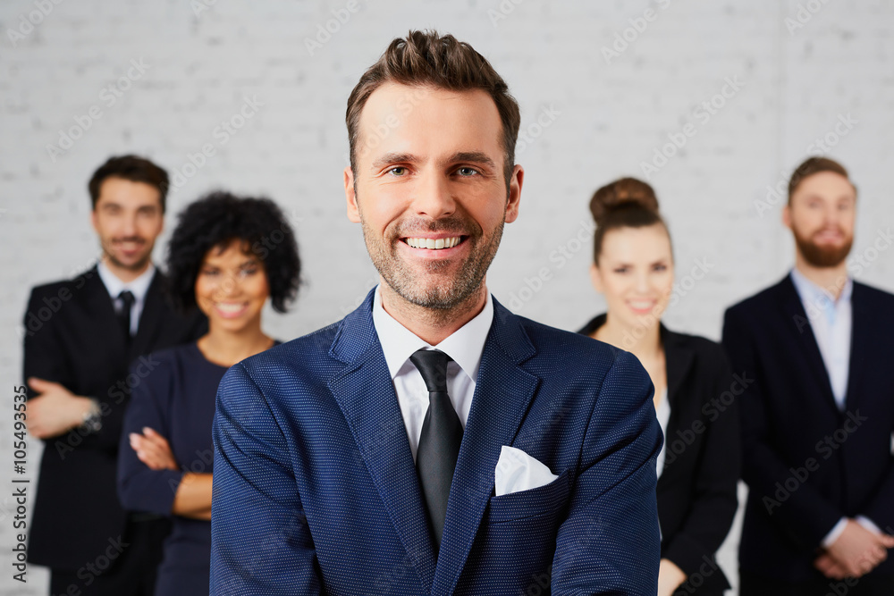 Portrait of confident company leader with business partners behi