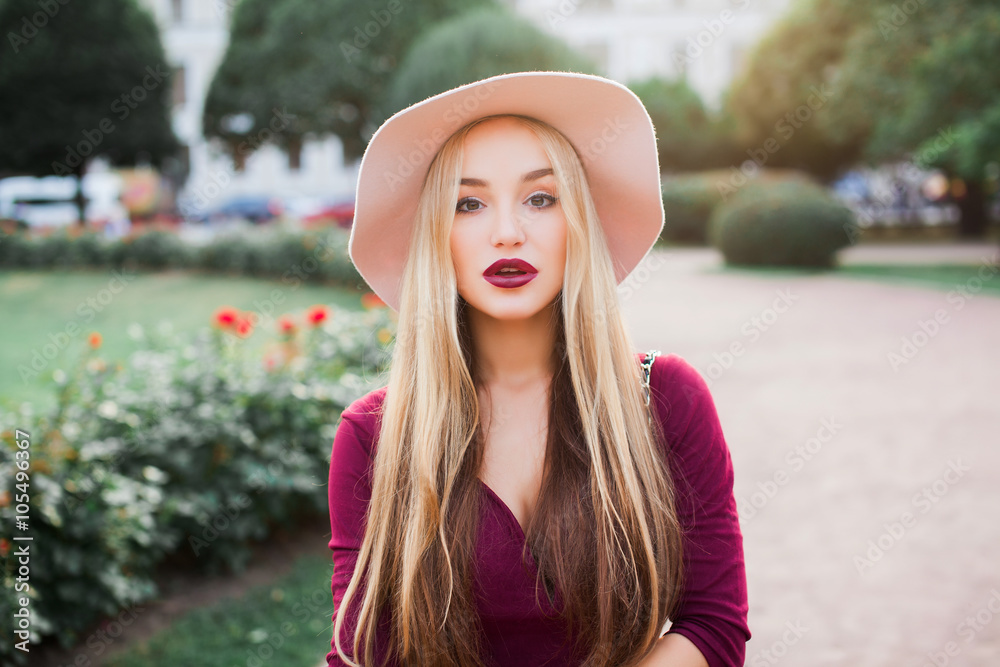 Outdoor fashion portrait of young seductive woman,wear casual outfit,posing with bag and hat,big pink hat blonde with red lips posing on the street,full red lips,big blue eyes,long hairs,keratin hair