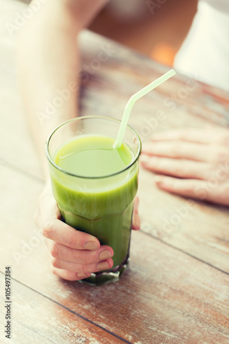 close up of woman hands with green juice