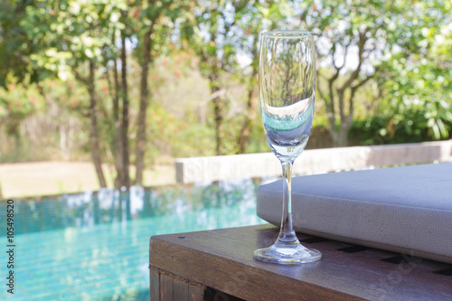 Glass of wine on the bed beside the pool