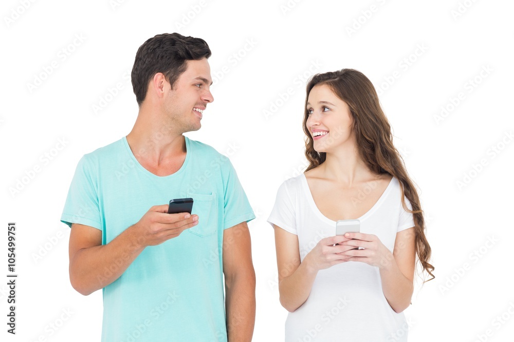 Smiling couple using their smartphones Smiling couple using their smartphones