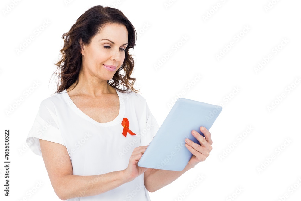 Woman with red aids awareness ribbon using tablet Woman with red aids awareness ribbon using tablet