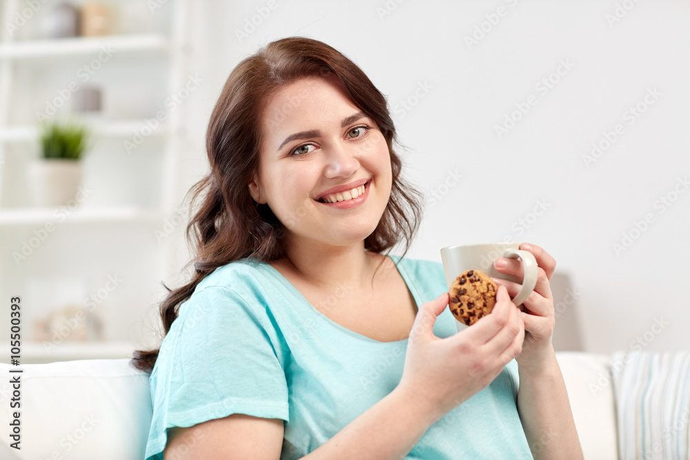 happy plus size woman with cup and cookie at home happy plus size woman with cup and cookie at home