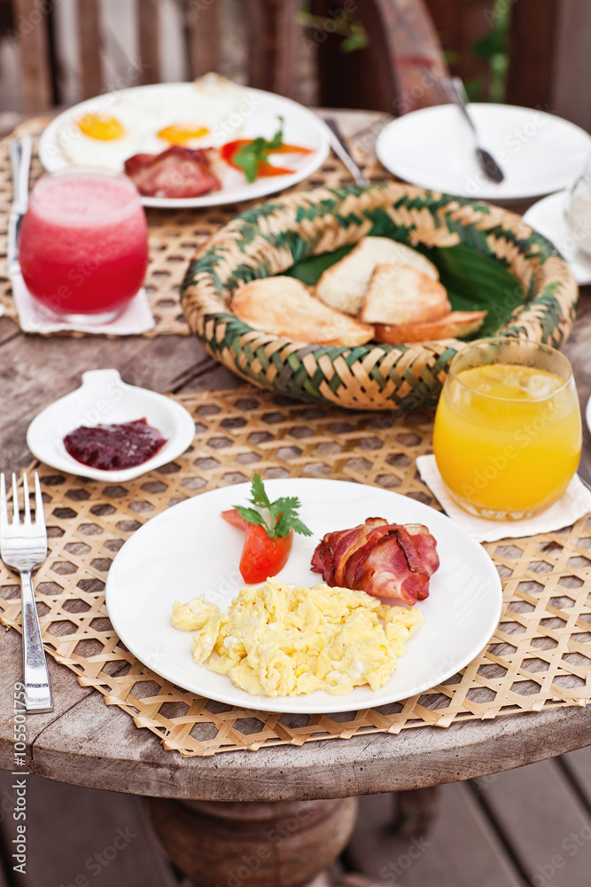 Perfrect healthy breakfast on patio in summer day. Fried eggs, cappuccino, fruits and muesli. Yummy and delicious