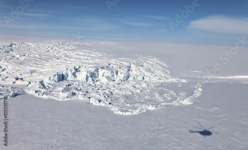 Aerial view of iceberg in frozen Arctic Ocean and helicopter shadow