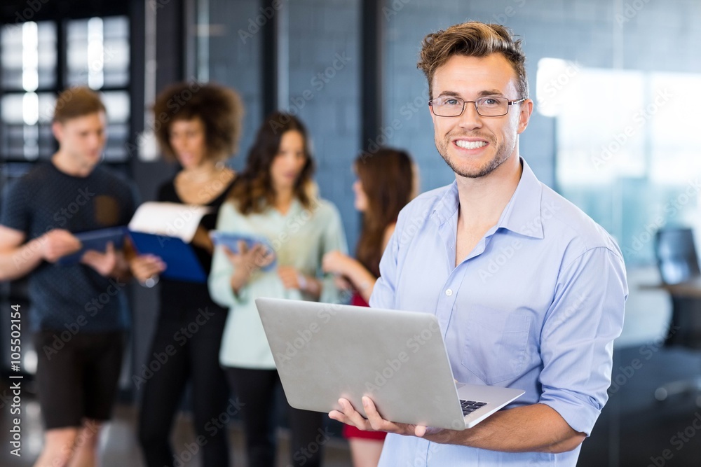 Portrait of man holding a laptop and smiling