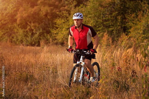 Man is riding a mountain bike in the field