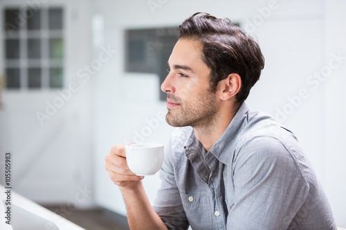 Thoughtful young man holding coffee cup 