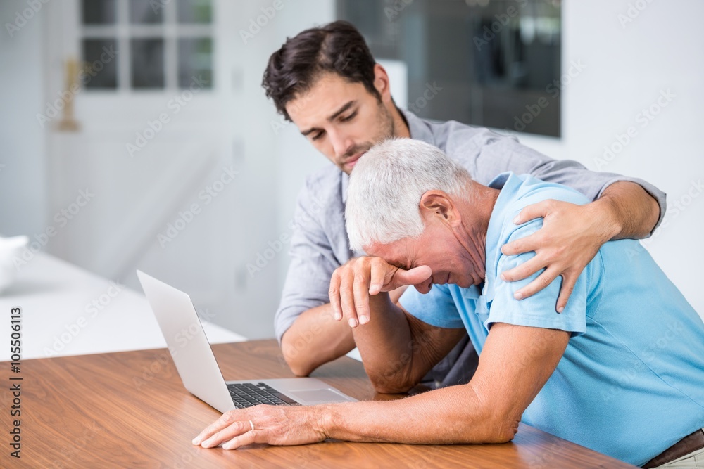 Obraz premium Son comforting tensed father sitting at desk 