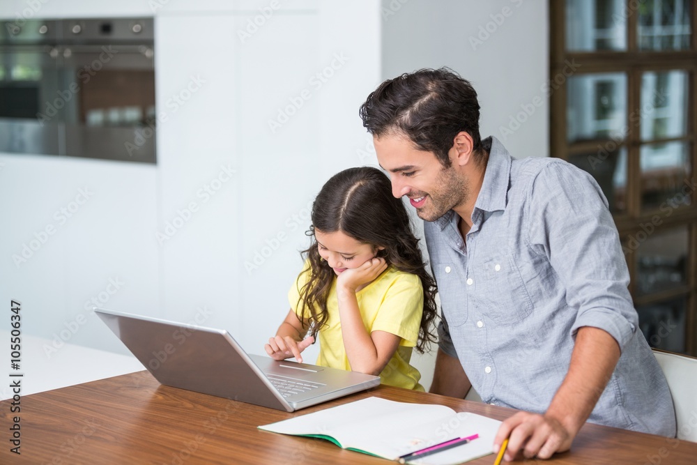 Smiling daughter working on laptop with father Smiling daughter working on laptop with father