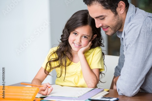 Portrait of smiling daughter with father at desk