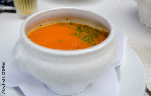 Pumpkin soup and parsley leaf in a white bowl