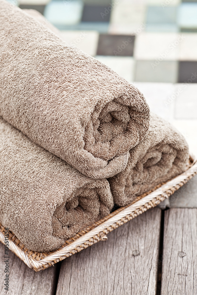 Brown towels in wicker basket at a luxury swimming pool
