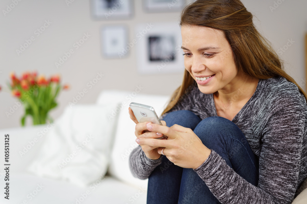moderne junge frau sitzt auf dem sofa und liest eine nachricht auf ihrem smartphone moderne junge frau sitzt auf dem sofa und liest eine nachricht auf ihrem smartphone