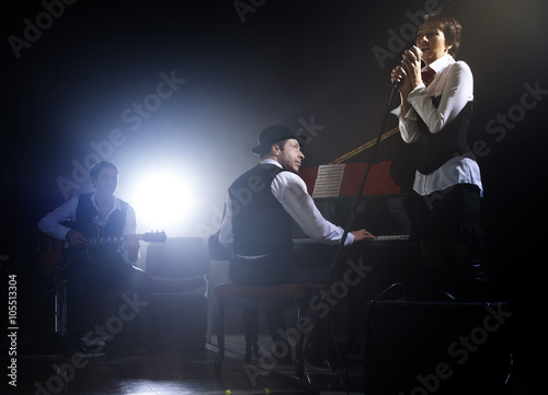 Photography Girl singing into retro microphone to the accompaniment of piano and guitar