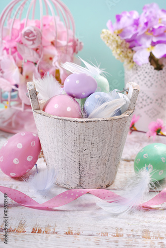 old wooden bucket with easter eggs and feathers