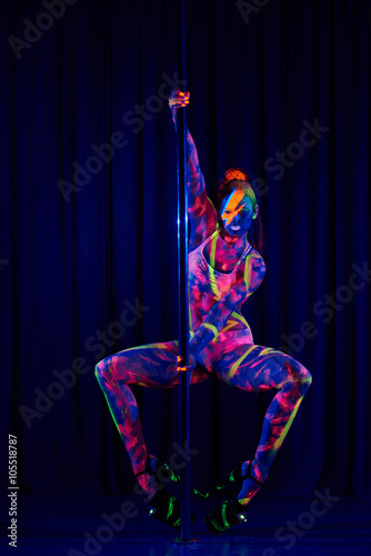 Fotografie Female pole dancer in bright neon colours under ultraviolet (UV) light on backgr