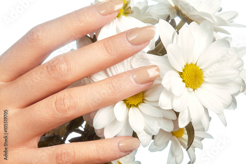 Beautiful female fingers with natural beige manicure touching spring flowers. Care about female hands, healthy soft skin. Spa & cosmetics. Close-up of beautiful fingers with nails polish

 photo