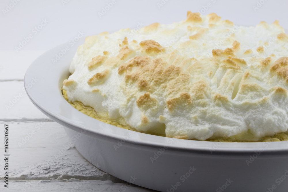 Close up of whole uncut lemon meringue pie on white rustic wood Close up of whole uncut lemon meringue pie on white rustic wood