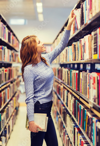 happy student girl or woman with book in library