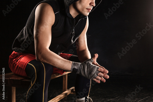 The muscular man sitting and resting on black