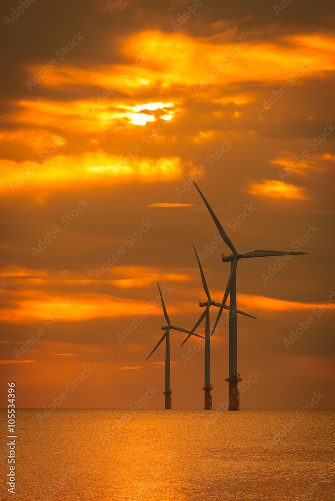 Obraz premium Sunset Offshore Wind Turbine in a Wind farm under construction on coast of England