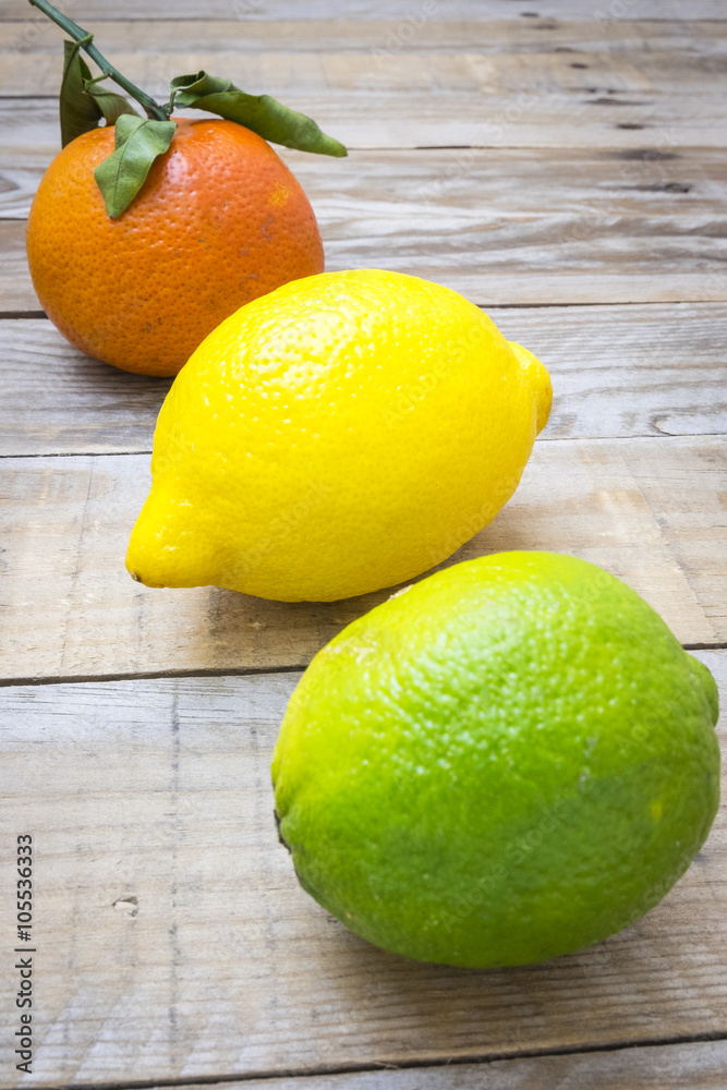 several mature citrus on a wooden table - lemon, lime and tangerine

