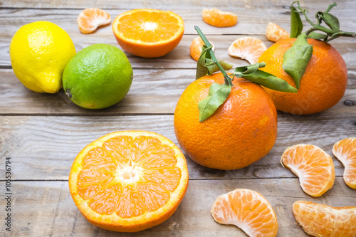 several mature citrus on a wooden table - lemon, lime and tangerine
