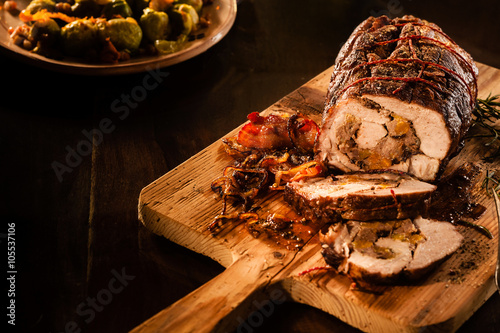 Roasted pork sliced with bacon on cutting board photo