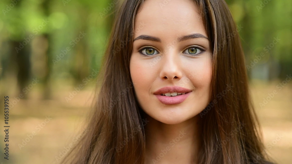 Beautiful smiling young woman against green of summer park. Closeup face Beautiful smiling young woman against green of summer park. Closeup face