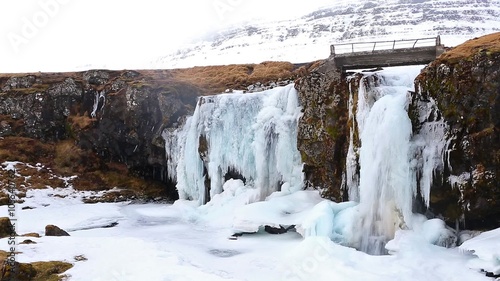 Frozen waterfall Kirkjufellsfoss near distinctive Kirkjufell mountain on the north side of the Snafellsnes Peninsula, late winter, Iceland photo