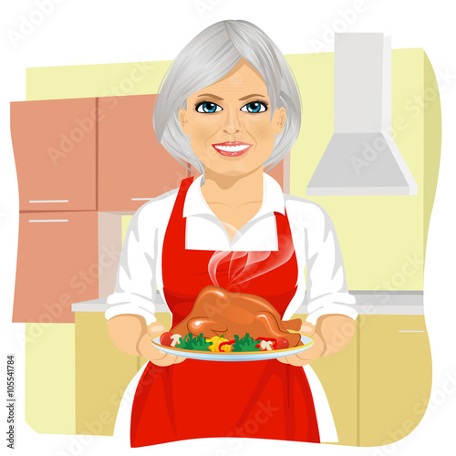 Sweet grandmother in red apron cooking traditional thanksgiving turkey