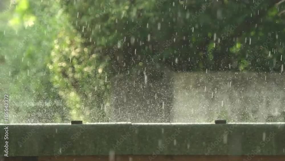 MACRO SLOW MOTION: Raindrops falling on the ground and splashing around and glittering in the morning sun