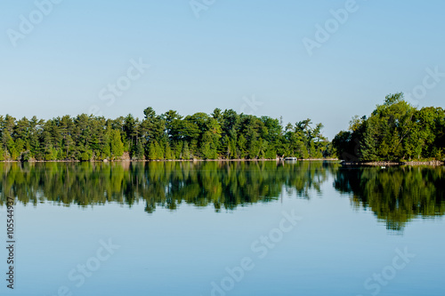 pristine lake in Canada with a blue sky and wilderness reflected in the lake photo