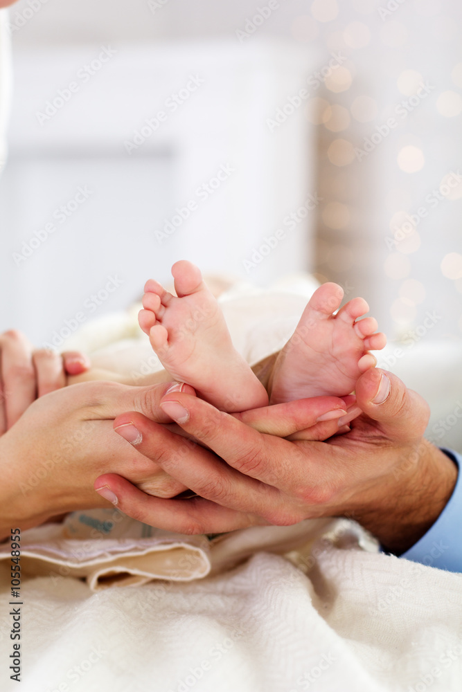 Parents are holding childs foots by hands
