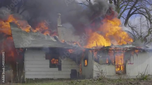 Large flames burn through the roof of a house 