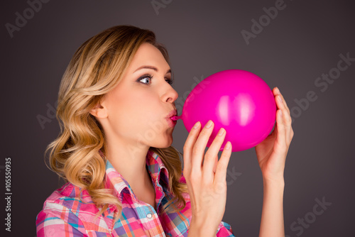 Valokuvatapetti Side view portrait of pretty woman blowing balloon