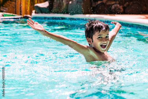 Young boy kid child eight years old splashing in swimming pool having fun leisure activity open arms