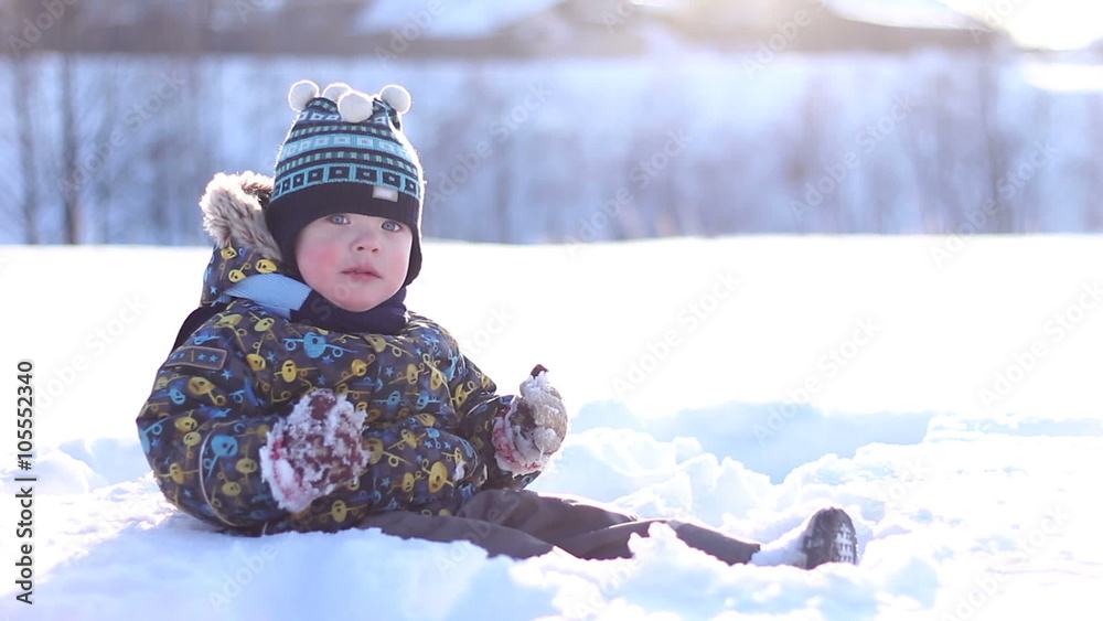 little boy in a winter cap playing in the snow