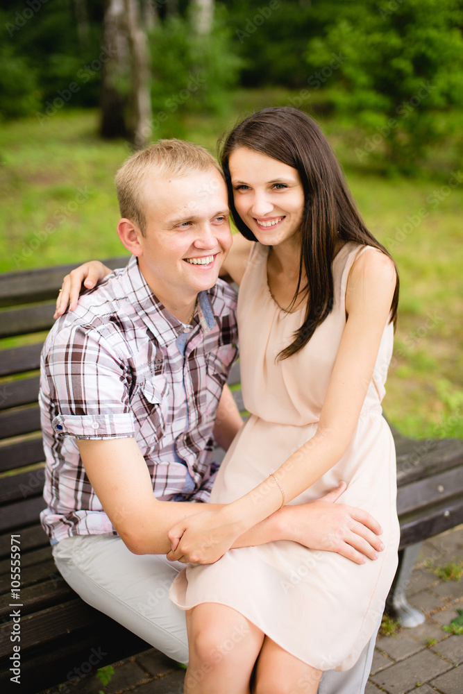 Young couple sitting together on bench in the park