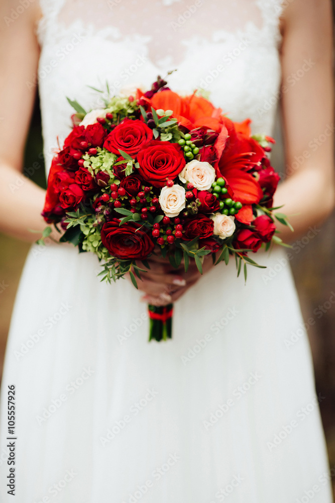 Magical beautiful young blonde bride in elegant dress with bouquet of red flowers Magical beautiful young blonde bride in elegant dress with bouquet of red flowers