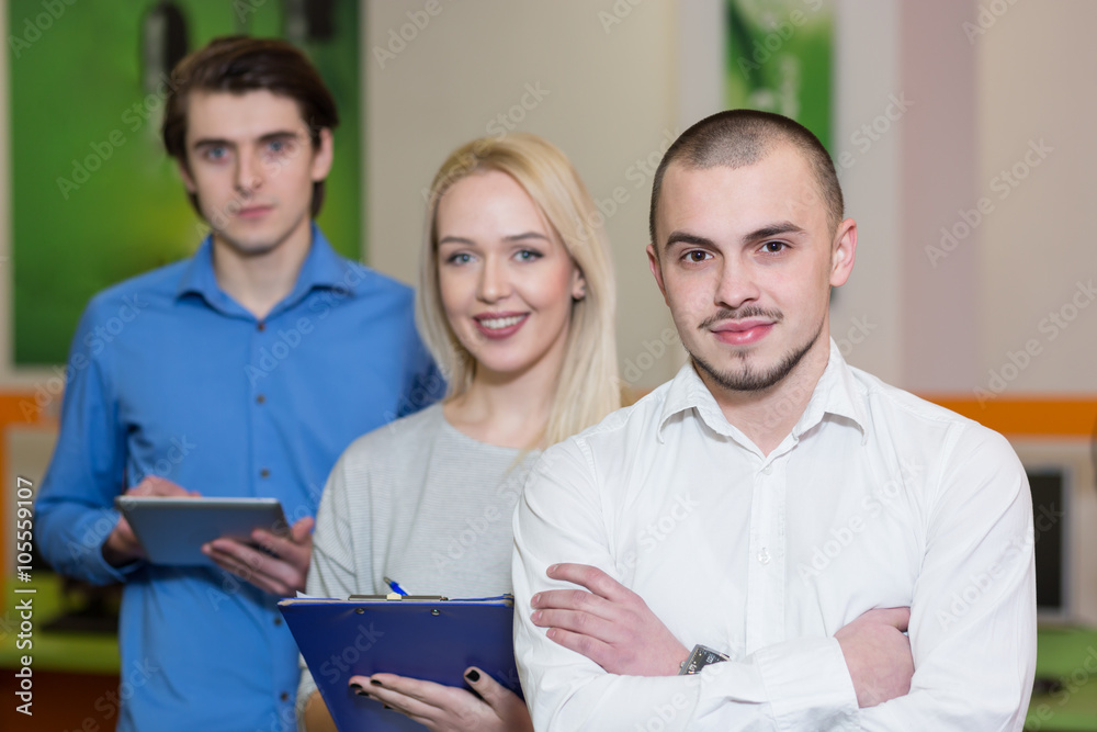 Team leader stands with coworkers in background Team leader stands with coworkers in background