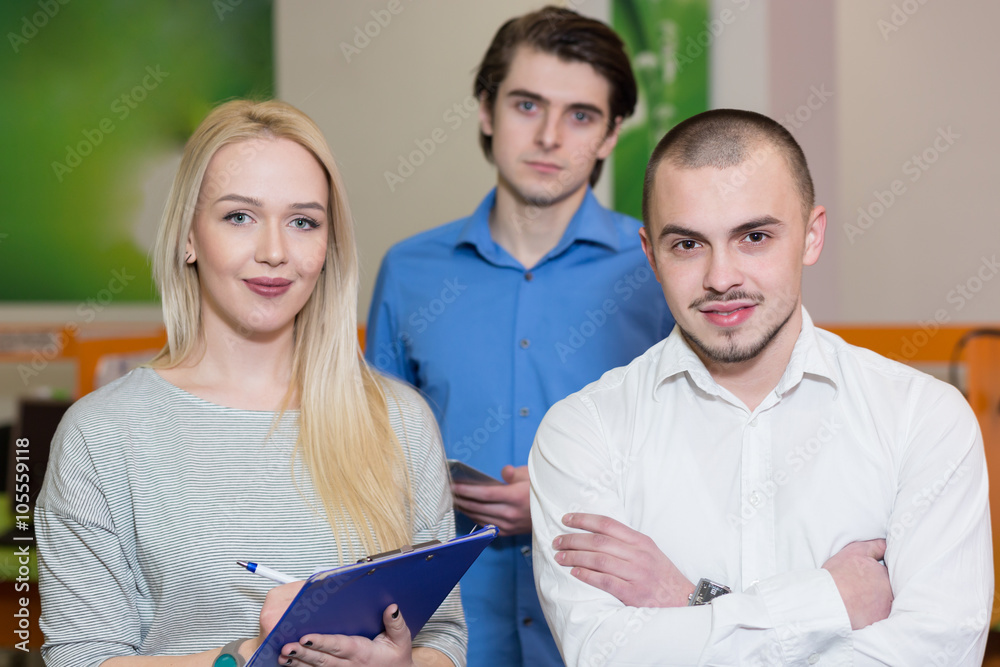 Team leader stands with coworkers in background Team leader stands with coworkers in background