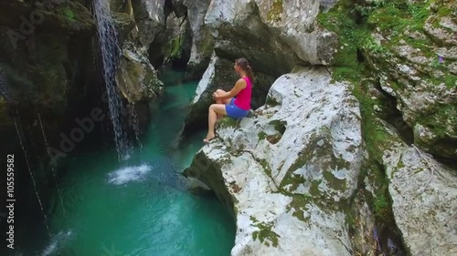 AERIAL: Young woman watching a waterfall in beautiful rocky canyon photo