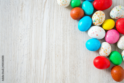 Easter candy eggs on white wooden surfae