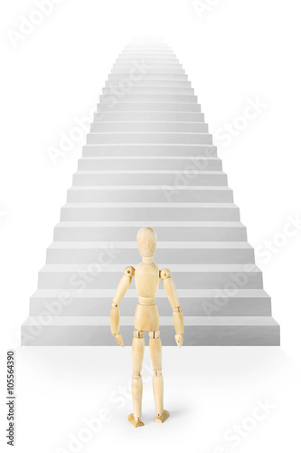 Man stands in front of a very high stairs ascending up. Abstract image with a wooden puppet
