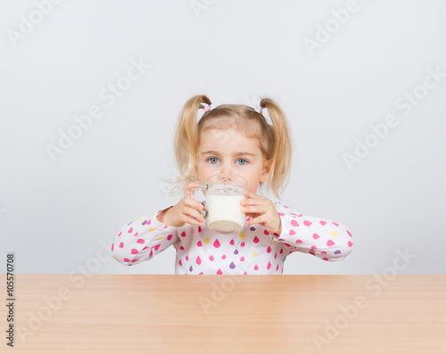 Happy little girl with a glass of milk.
