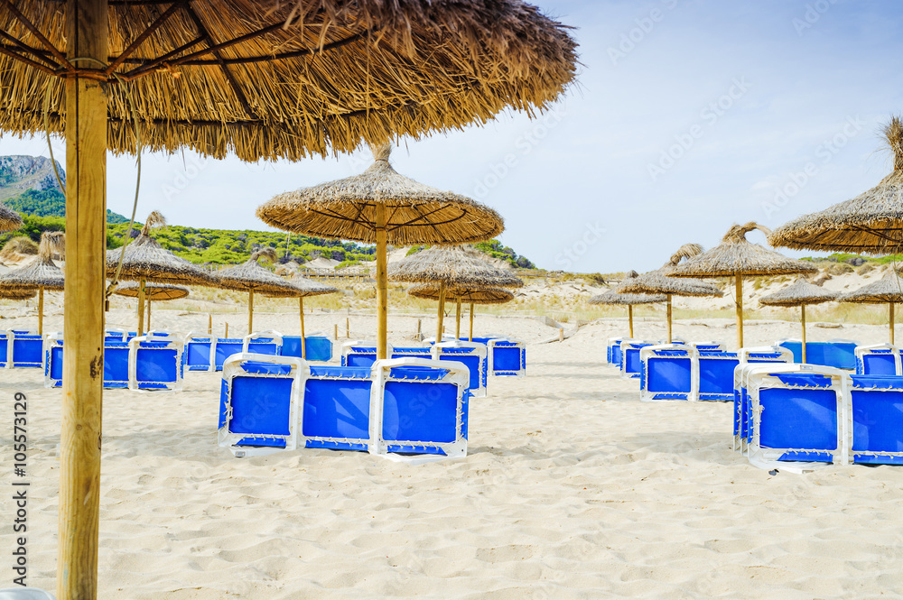 Umbrellas and sunbeds on the beach Cala Mesquida. Majorca. Balearic Islands. Spain