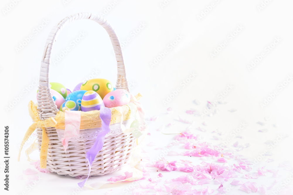 Colorful Easter eggs in white basket and pink delicate blossoms