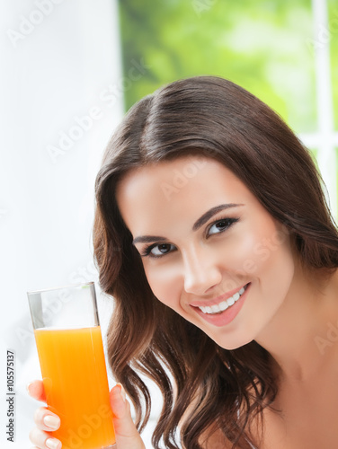 Happy smiling young woman drinking orange juice